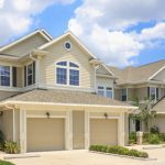 A large beige house with two garage doors.